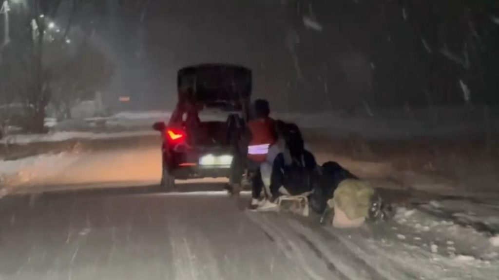 Patru tineri trași cu săniile de o mașină. Patru tineri trasi cu sanile de o masina